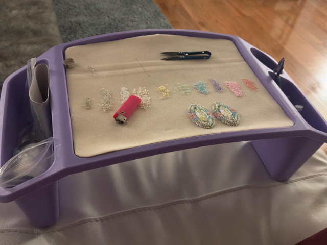 A purple lap tray with a bead mat and beadwork project on it