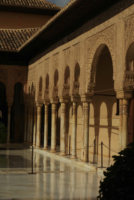 Photograph of tall white columns with extremely detailed heads o  top, on a shining white marble floor