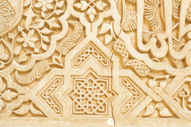 Photo of a closup of carvings in white stone eith inrichten and detailed geometric patterns