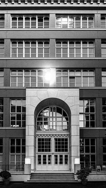 Eine Hausfassade mit hohem Eingangsportal
in der Mitte eine Laterne und zwei Topfpflanzen
neben dem Eingang.
--------------------------------
A house facade with a high entrance portal
a lantern in the center and two potted plants
next to the entrance.