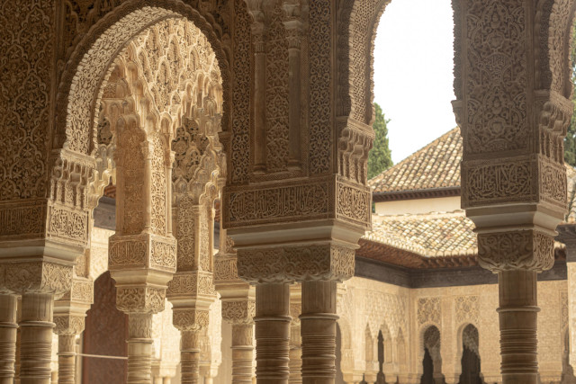 Photo of white stone arches covered in detailed carving; the tops of columns are visible, and looking through the arches, more columns and more arches, all covered in detailed carving