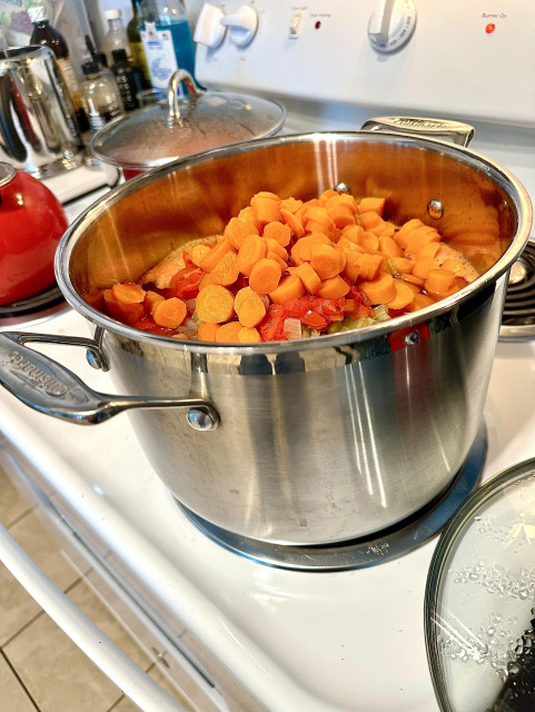 Very large Cuisinart pot on white electric stove, about 5 quarts cut up: carrots, onion, red peppers, celery, and 2 kinds tomatoes. All veggies but tomatoes were precooked in an Instant Pot.  