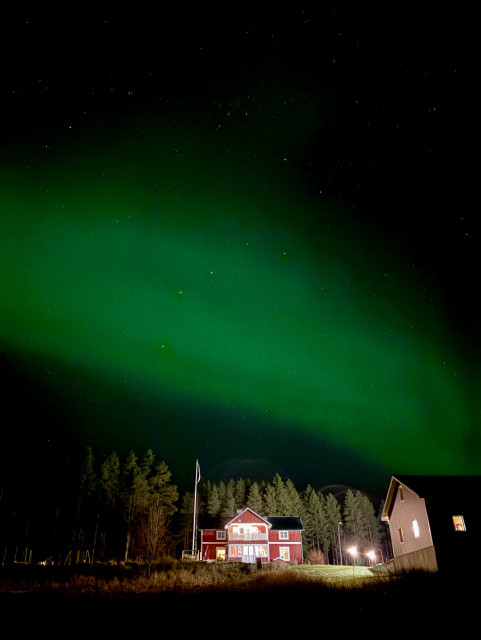 A misty green aurora above a farm house.