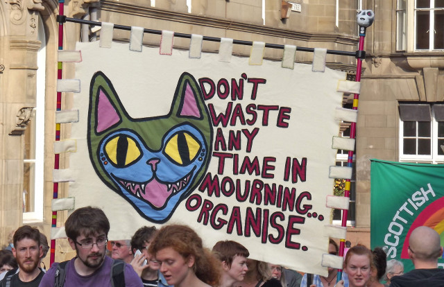 People on a demonstration holding a banner with the slogan "Don't waste any time in mourning ... Organise"