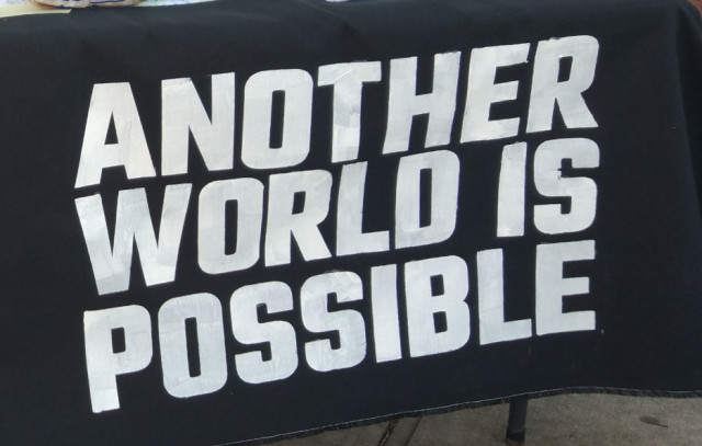 A closeup of a black banner with white text, saying "Another World is Possible"