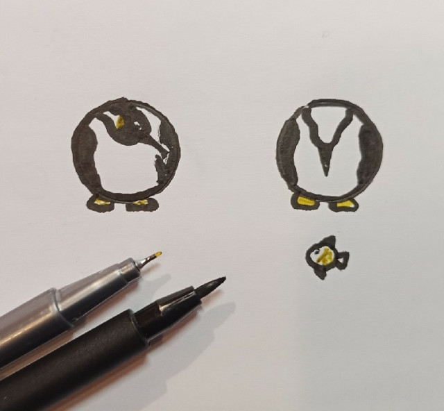 Scribble of two small. very circular penguins looking at a very tiny, round fish. A black brush pen and a yellow fineliner next to them on the paper.