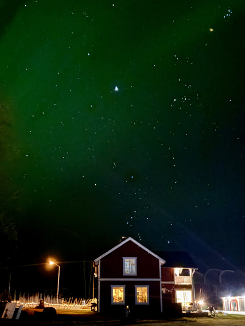 All four images are of a red wooden house on the Swedish countyside with a starry sky and green aurora behind it. The images are from slightly different angles, some showing a bit more of the surrounding pine trees.