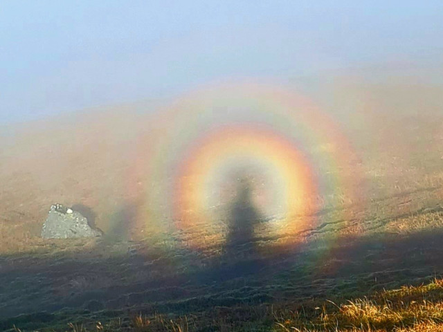 A shadowy figure on a mountainside surrounded by circles of colour.