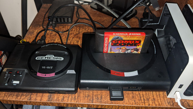 A Sega Genesis Mini console next to an Analogue Mega Sg clone console with Comix Zone inserted.