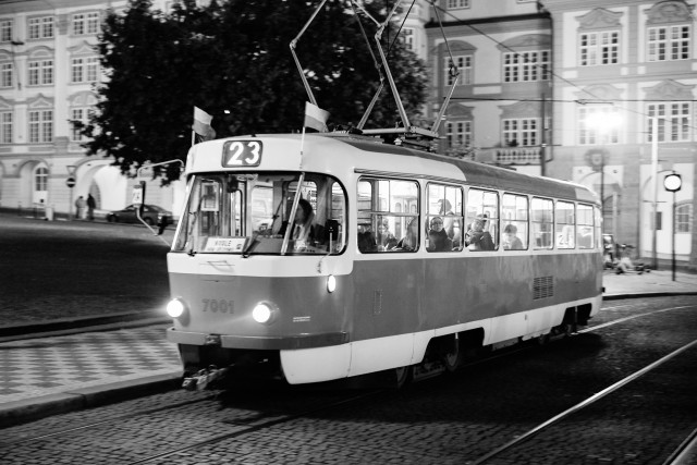 Schwarzweiße Fotografie einer alten Straßenbahn bei Nacht.