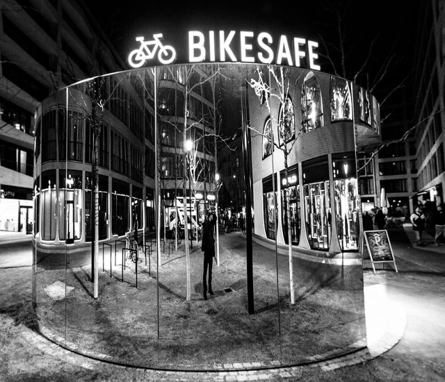 Umgeben von Modernen Wohn und Geschäftshäusern steht ein großer verchromter Zylinder in dem Fahrräder Aufbewahrt werden.
-------------------------------------------------------------------------
Surrounded by modern residential and commercial buildings, there is a large chrome-plated cylinder in which bicycles are stored.