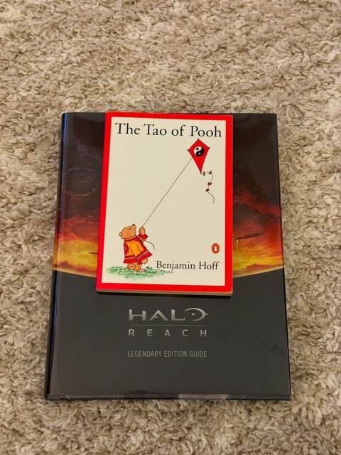 The book The Tao of Pooh by Benjamin Hoff sitting on a Halo Reach book. 