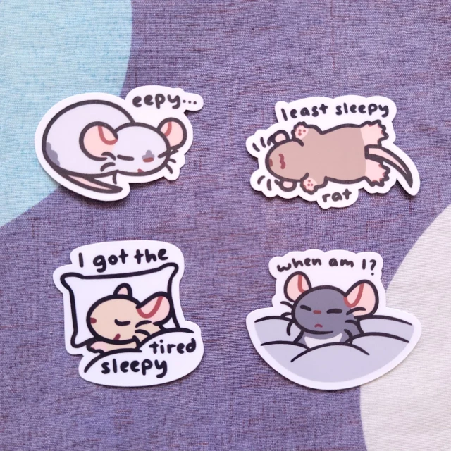 eepy sleepy rat sticker set
1. "eepy..." a blue point Siamese rat sleeps
2. "least sleepy rat" a brown rat lies on their back sleeping
3. "I got the tired sleepy" a cream rat lies in bed, covered by a blanket
4. "when am I?" a black Berkshire rat pokes their head out of a mass of blankets