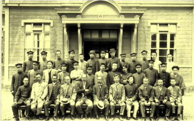 Formal black and white class photo, with 36 men in 3 rows, with Chika Kuroda standing at the end of the second row. She is wearing a kimono, with her hair up in traditional style.