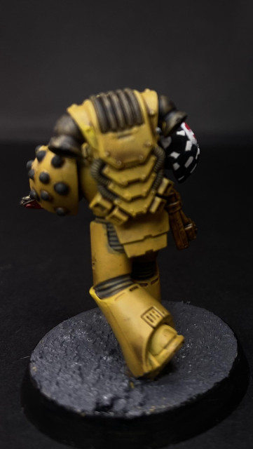 Rear of a Lamenters Space Marine. Yellow armour, checkered Pattern Visible on the shoulder pad.