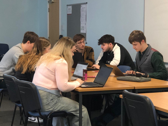 Me (centre) sitting around a table with students from De Montfort University, teaching them about media and politics. There are five students using laptops.