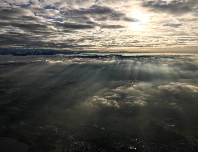 Afternoon flight over clouds with sunrays in the fog.