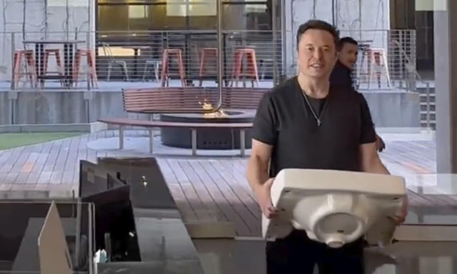 Musk entering Twitter HQ, October 2022, with publicity stunt sink.