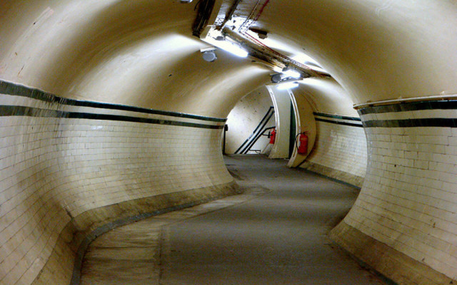 A snaking, white-tiled pedestrian tunnel on the London Underground. 