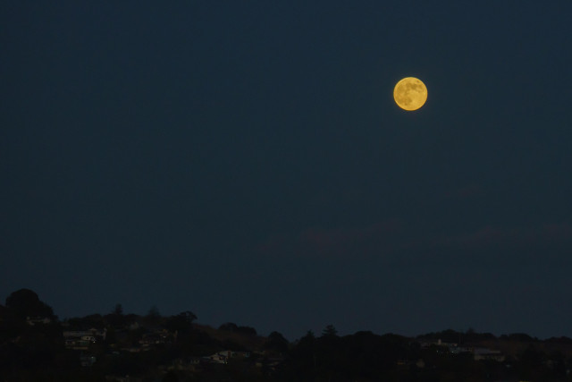 Moon rising over hills with houses on them