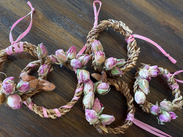 Five small wreath ornaments made of dried iris leaves and rosebuds. 