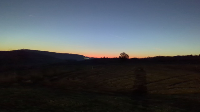 Sonnenuntergang: ein bunter Farbstreifen am Horizont. Das Land davor schwarz, der Himmel dunkelblau