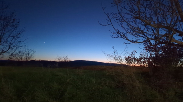 Sonnenuntergang: ein bunter Farbstreifen am Horizont. Das Land davor schwarz, der Himmel dunkelblau