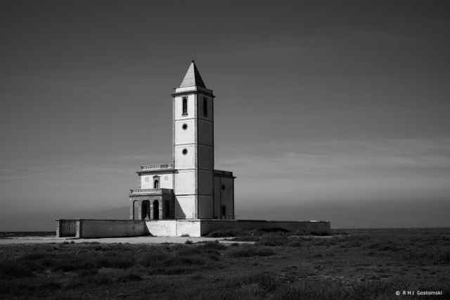 A black-and-white photo of a church on the beach at Cabo de Gata, Spain. This was taken early morning and the sun catches the front elevation of the church beautifully.