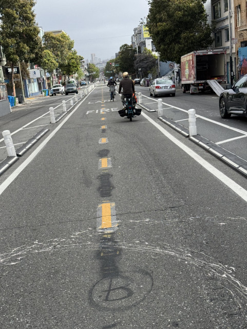 A photo of the bike lane on Valencia street with with rubber bumpers on the ground to keep cars from crossing into it. 