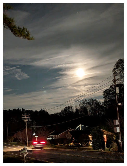 night. residential strip on a two lane road under an almost-full moon.