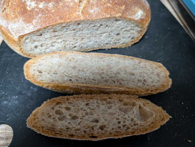 Das Brot im Anschnitt, davor liegen 2 abgeschnittene Scheiben, so dass die Porung zu sehen ist 