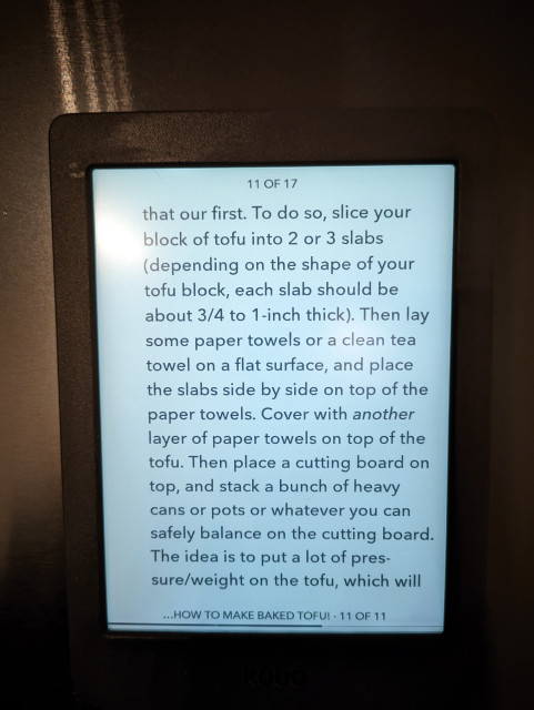 Front view of a Kobo Nia attached to a refrigerator. The text is from a recipe describing how to press and bake firm tofu. 