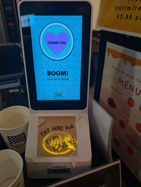 A TIPJAR PoS payment processing unit with a post-it reading TAP HERE FOR TIPS ONLY!