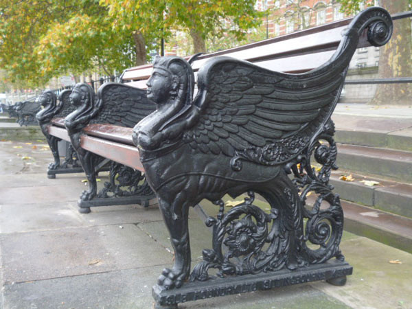 Bench on London's Embankment with black winged sphinxes at each end and in the middle, with their wings forming the armrests.