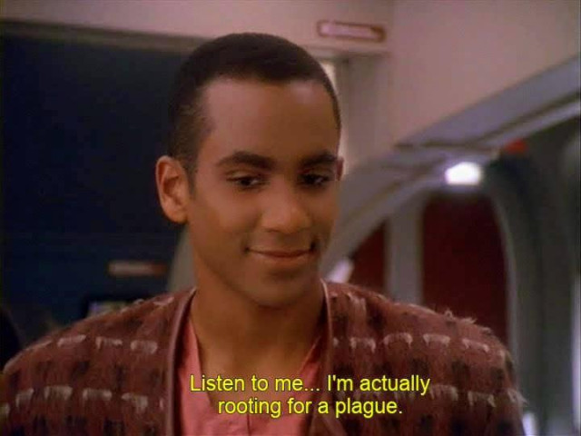 DS9 scene. Young Jake Sisko is pictured wearing civilian clothes not a uniform because he's not an officer just a lad finding himself and life and meaning on a deep space space station. Here, he's kind of smiling and lost in thought. Closed caption reads, "Listen to me... I'm actually rooting for a plague."