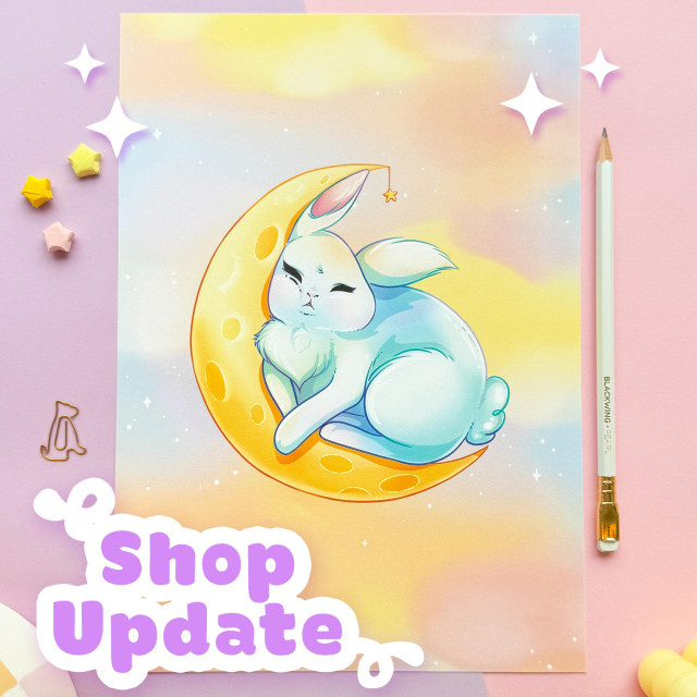 A photo of a print of a bunny sleeping inside of a crescent moon on a pastel cloudy background.