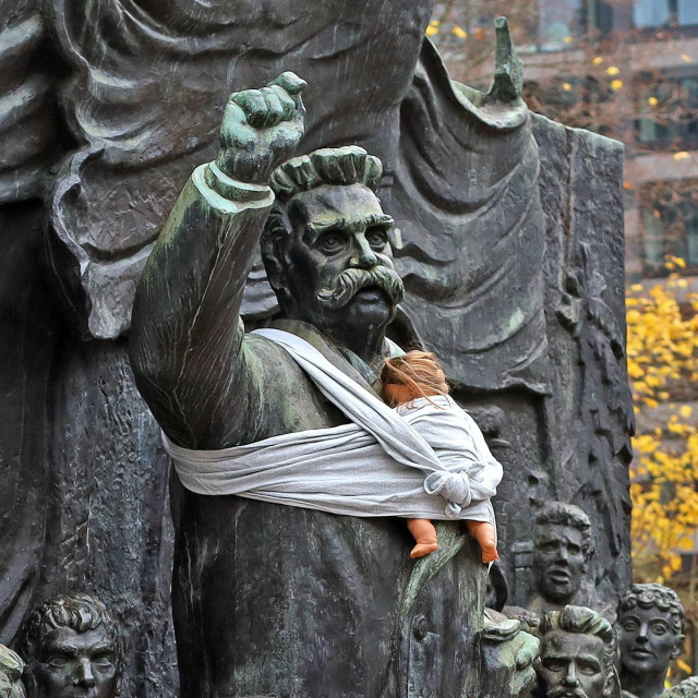 A historical statue of a man, symbolizing leadership and authority, is humorously adorned with a white baby sling carrying a doll. This creative intervention is part of a campaign by Arena Idé, highlighting the unequal division of parental responsibilities in Sweden. It calls attention to the underrepresentation of fathers in caregiving roles, despite progressive parental leave policies. The statue, set against a backdrop of urban architecture and autumn leaves, represents the campaign's goal to challenge societal norms and advocate for shared parenting responsibilities.