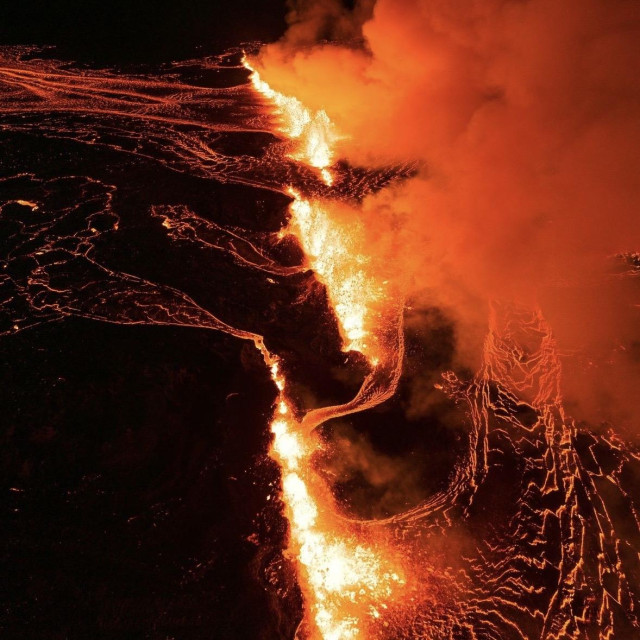 Drone view in the dark of a big crack divided into three parts with lava flowing in all directions.