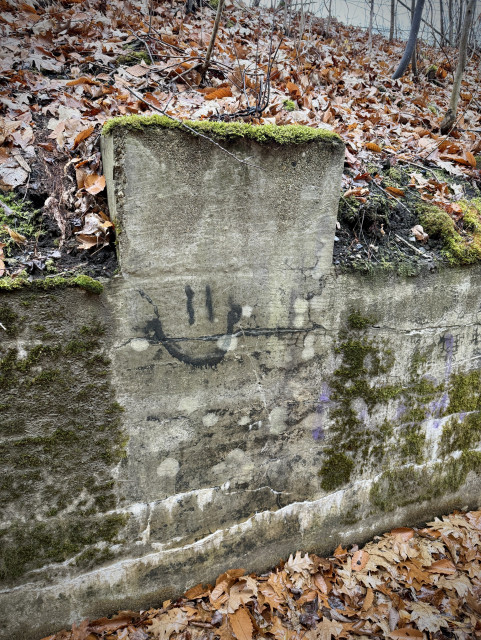 Old railroad track side wall cement, some one has painted a smiley face