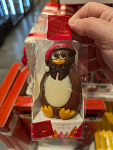 A fist-sized chocolate penguin, reminiscent of the Linux mascot, wearing a red Santa hat.