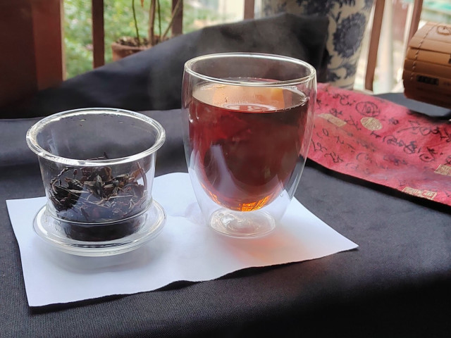 A look at the tea and basket from the side now.  Shortly after taking this picture I took the first sip and, sure enough, it was weaker than I'd expected.  The flavours were all good.  There wasn't a hint of bitterness at all outside of the "nutty" bitters that I so adore in a well-prepared tea.  No acrid flavours whatsoever, even despite that distinct citrus-like aroma gently lurking behind the fruity orange sensation.

But it was all very distant, like I was drinking a cup of tea a few hundred metres away from me.  Good tastes and scents, but too weak.  Not quite watery, but definitely underwhelming.  When I next make this I'm going to double the amount of tea I use, keep the same wash, and then watch carefully while it brews until it hits the perfect colour for a true black.