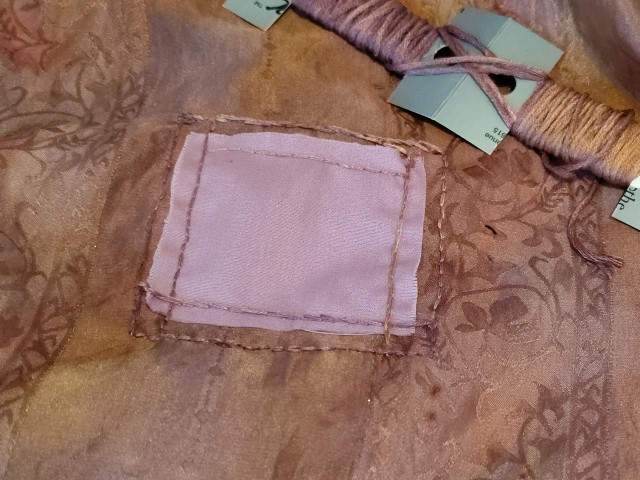 I added an applique patch that pops against the scarf. The patch is a lavendar color against the mauve, pink, and orange-gold scarf silk fabric. The patch also covers the giant holes I'm mending.