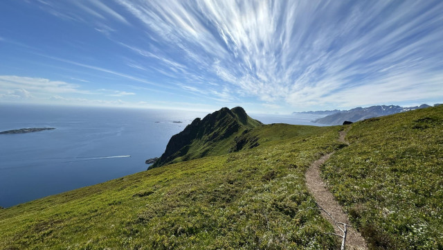 A narrow path about the blue ocean with striking lines of clouds in the sky