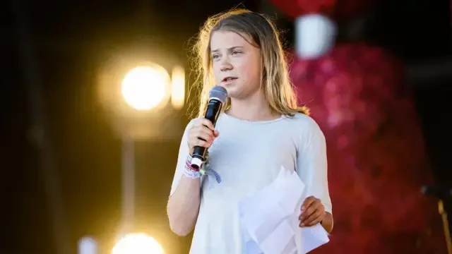 Photo of Greta Thunberg, holding a microphone and speaking at a recent event.