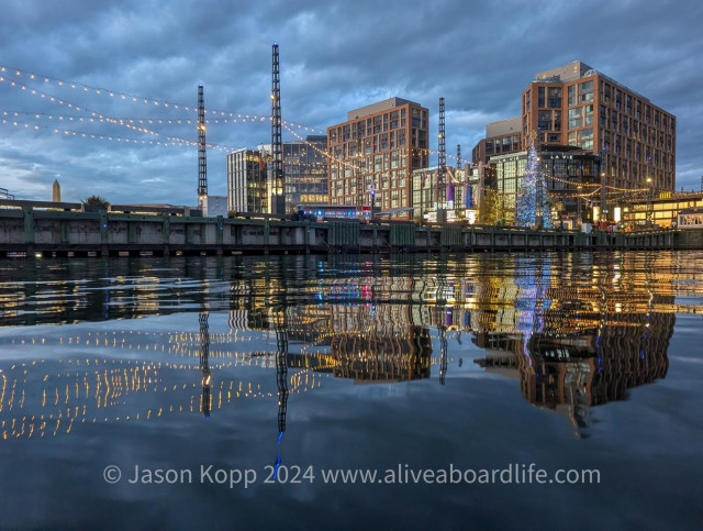 District Pier with Christmas lights and yes, a lit Christmas tree reflect in still water with wharf phase I buildings and dark clouds overhead