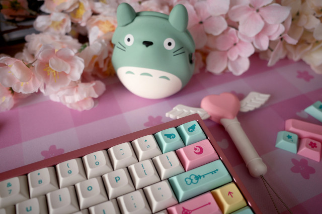 Desk with a pink themed mechanical keyboard and green Totoro.