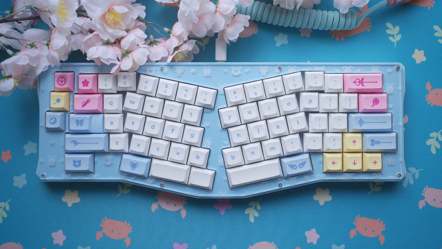 Blue alice layout keyboard with pink, yellow, and blue magic girl keycaps on a crab in the sea pattern deskmat.