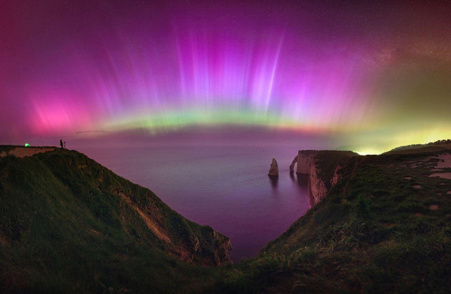 "This panoramic image captures a sky filled with vibrant auroras stretching 180 degrees from the southwest to the northeast.

"The display includes hues of pink, violet, and blue, with a green band near the horizon."