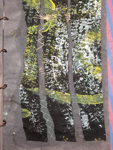 Abstract collage on dark paper: three irregular vertical columns of black paper, printed in yellow and white with corn on the cob. In the spaces between, beige and reed-green abstract embroidery with crosses, lines and a fan-like structure. Right side of the embroidery.