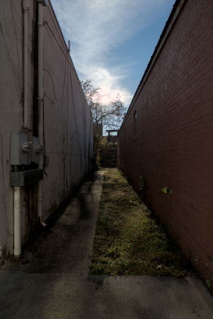 The space between two buildings, the sun framed squarely between them behind the clouds.